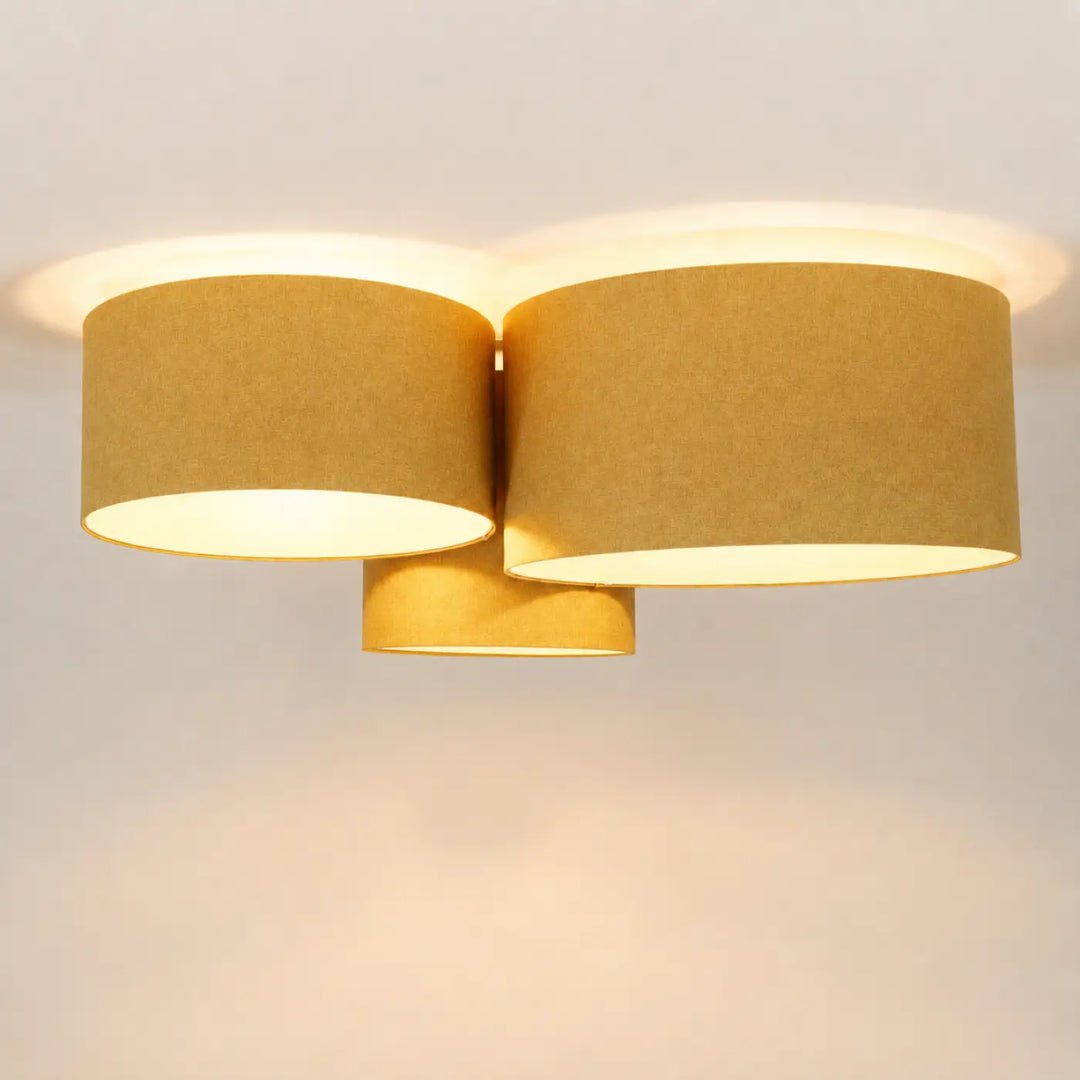 Luminaire plafonnier trio boho elegant avec deux abat-jours cylindriques en tissu moutarde et lumière naturelle chaleureuse