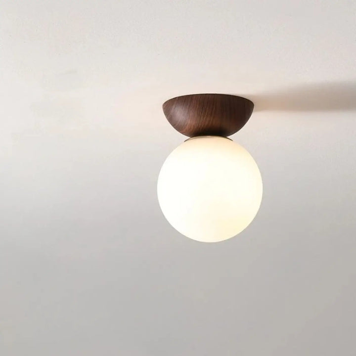 Luminaire plafonnier oako avec base en bois foncé et globe lumineux en verre dépoli pour un plafonnier design épuré