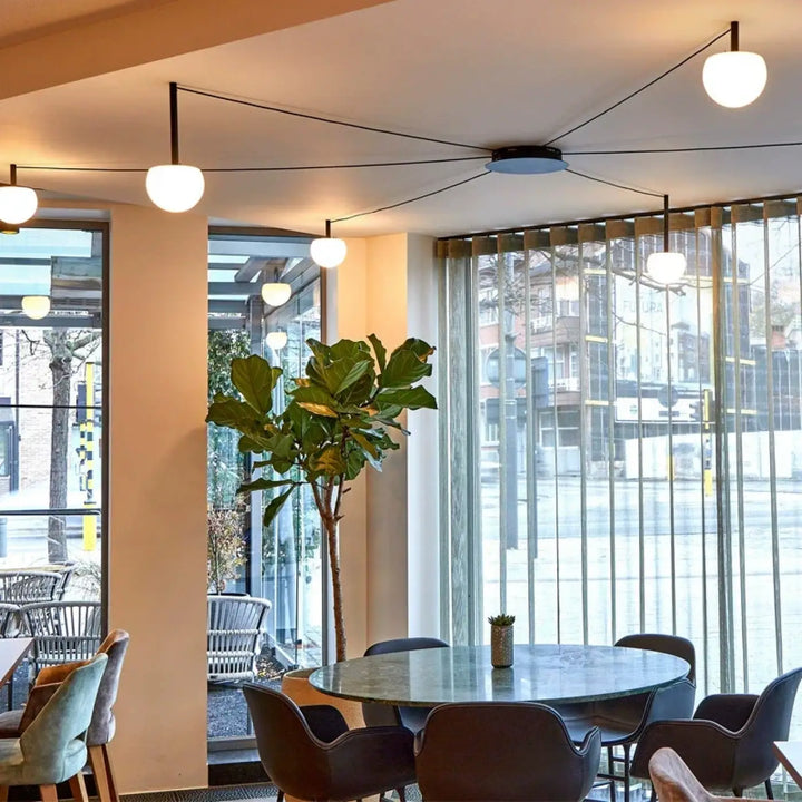 Plafonnier design aiko avec suspension luminaire, table ronde en marbre gris foncé et pieds métalliques noirs pour décoration intérieure univers déco