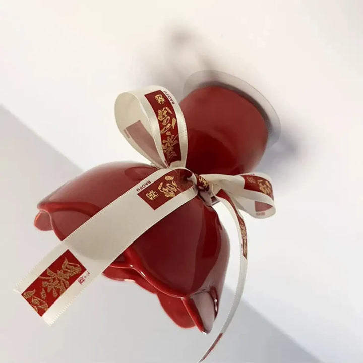 Luminaire plafonnier en céramique rouge brillant avec nœud décoratif blanc et motifs dorés pour décoration intérieure d’un objet pensé