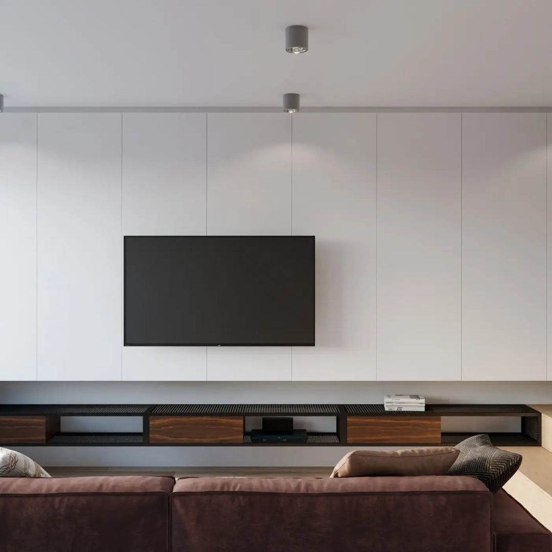 Plafonnier tiube gris avec forme minimaliste installé sur mur blanc avec télévision écran plat noire montée