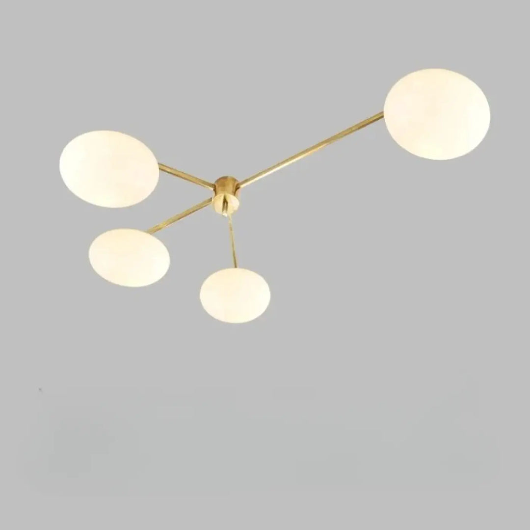 Plafonnier moderne xilys en laiton avec quatre globes en verre blanc et bras graphiques élégants
