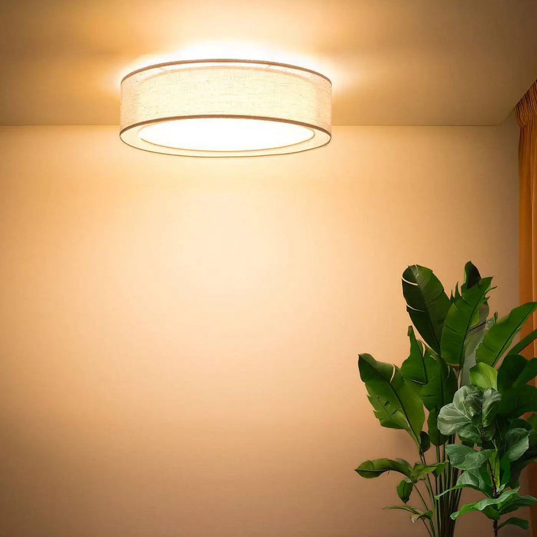 Luminaire plafonnier rond beige avec abat-jour en tissu texturé écru diffusant une lumière chaude et douce