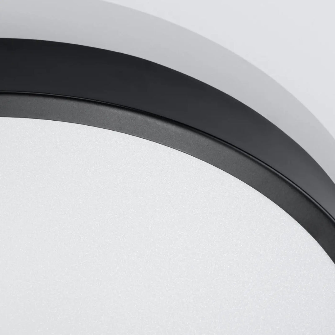 Luminaire plafonnier rond noir avec cadre circulaire mat et diffuseur blanc givré pour une recherche d’un éclairage aux couleurs intemporelles