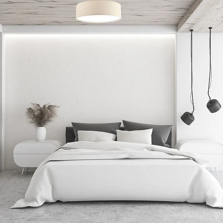 Luminaire plafonnier rond mesh en tissu champagne créant une atmosphère chaleureuse au-dessus d un lit minimaliste blanc
