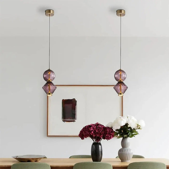 Deux suspensions luminaire slira avec globes en verre soufflé violet facetté et accents en métal doré élégant