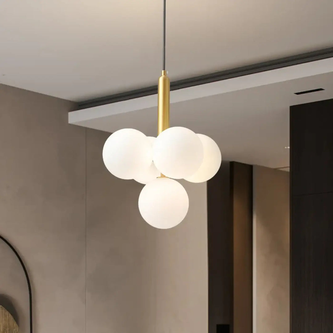 Suspension luminaire dinah avec quatre boules rondes en verre blanc milky white suspendues à une tige métallique dorée