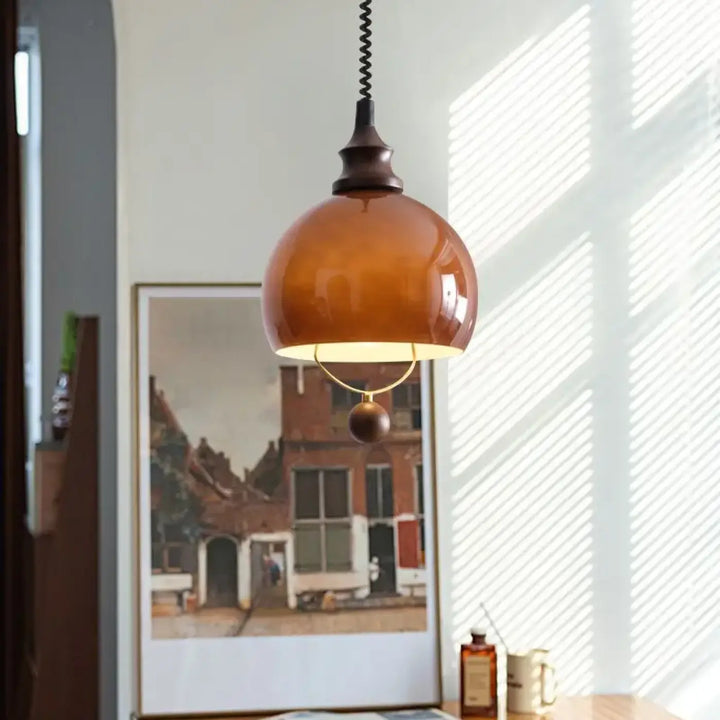 Suspension globe ambrée avec détail doré et boule décorative

