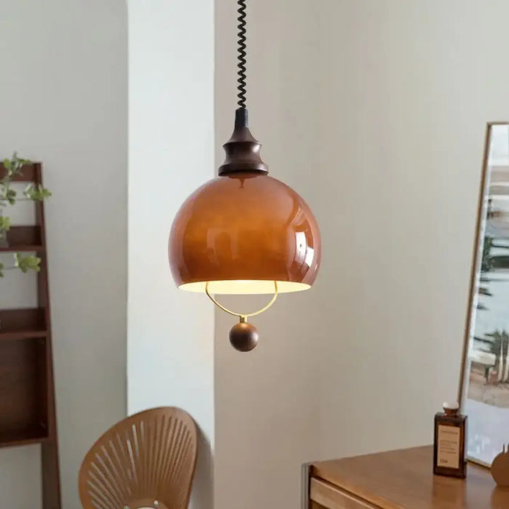 Suspension globe ambrée avec détail doré et boule décorative

