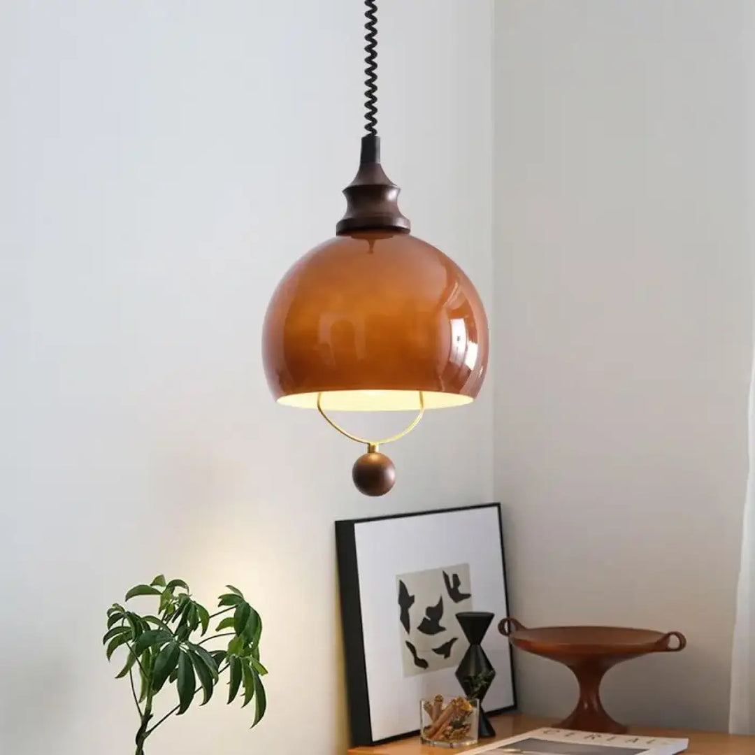 Suspension globe ambrée avec détail doré et boule décorative

