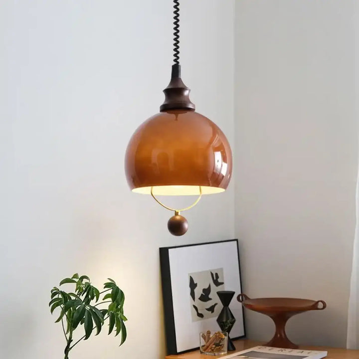 Suspension globe ambrée avec détail doré et boule décorative

