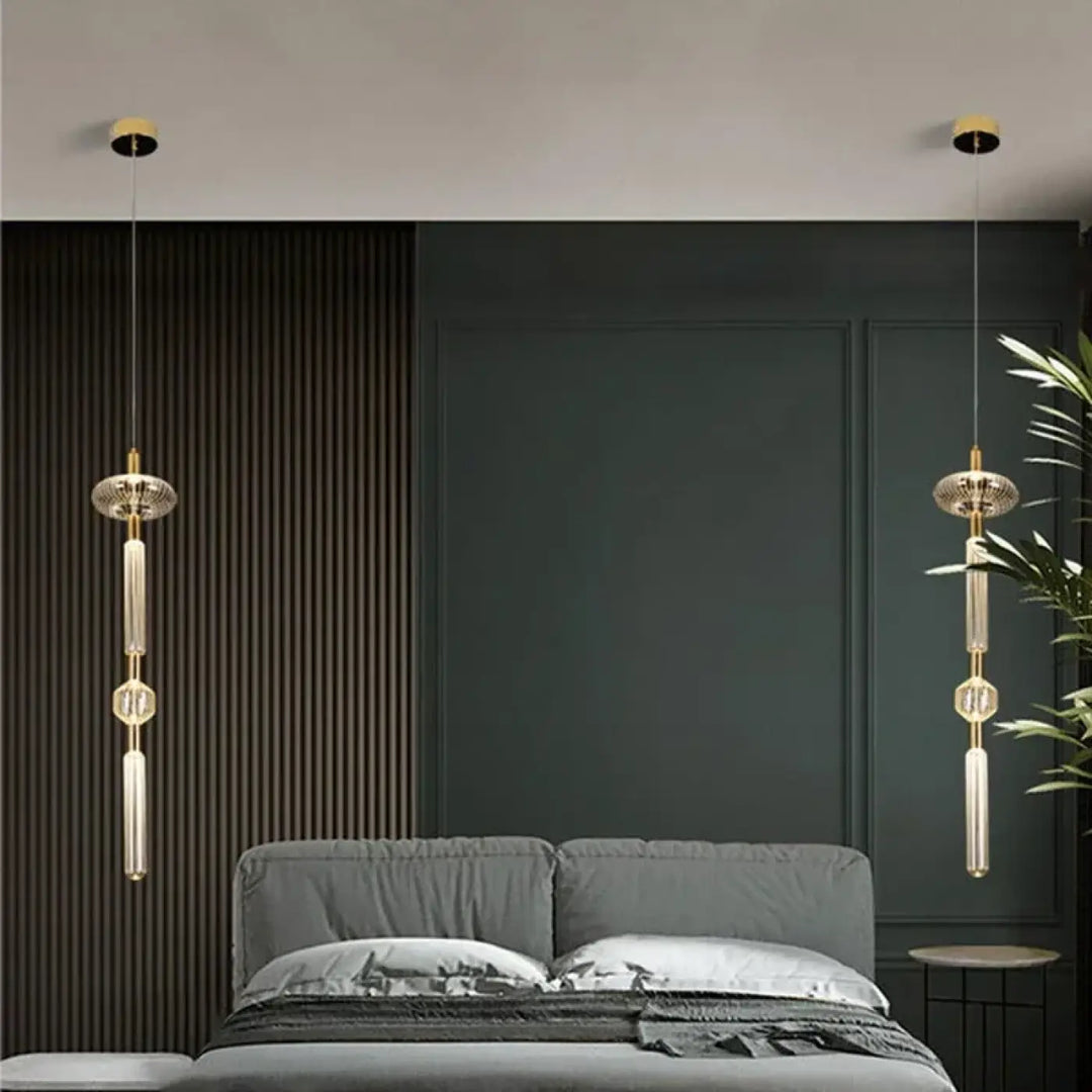 Suspension luminaire artistique or suspendue en verre cannelé avec ton doré et accents en cristal au-dessus d’un lit gris