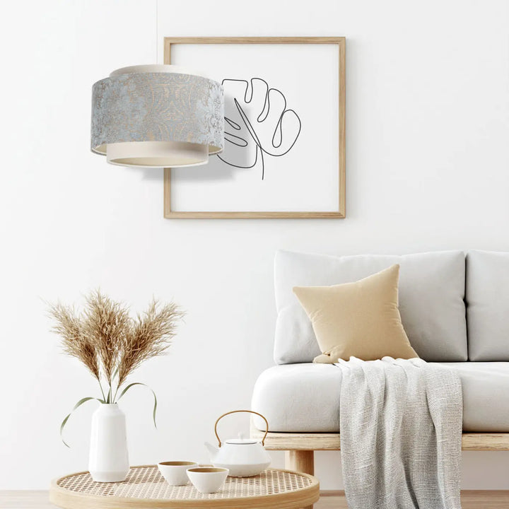 Suspension luminaire doblo avec abat-jour en tissu gris texturé et base crème beige bleu clair au-dessus d’une table basse