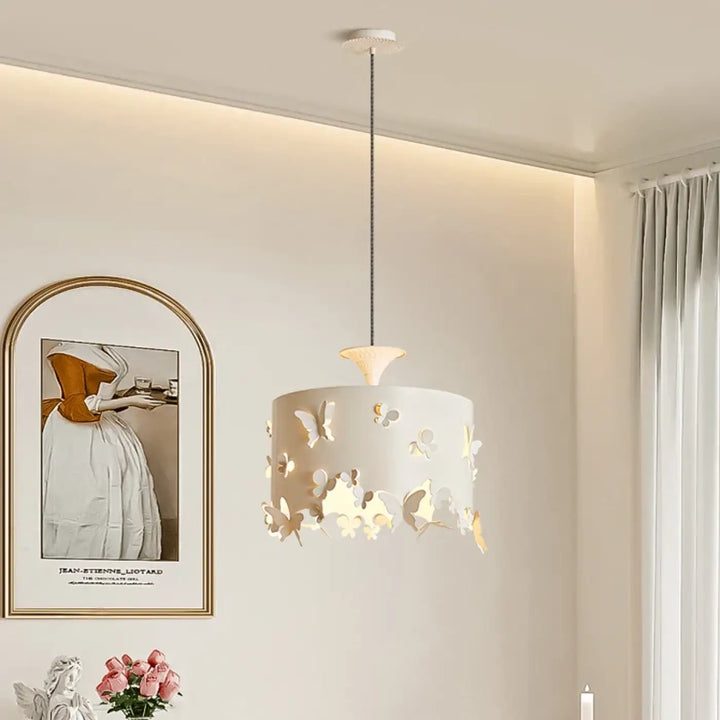 Suspension luminaire butelys cylindrique blanc avec découpes papillons diffusant une lumière chaude pour décoration intérieure au-dessus d’une table