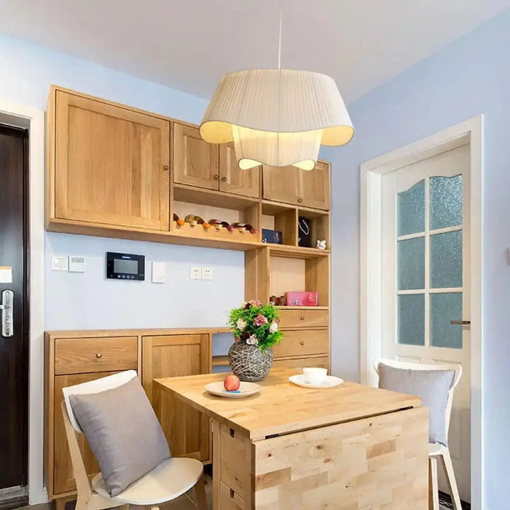 Suspension luminaire tusso en tissu blanc beige clair plissé au-dessus d une table à manger en bois choix d un éclairage élégant