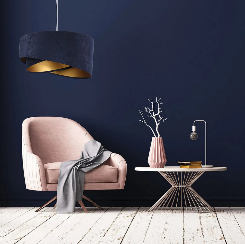 Fauteuil rose en velours avec pieds en bois et plaid gris devant une suspension bleu marine galaxy auric