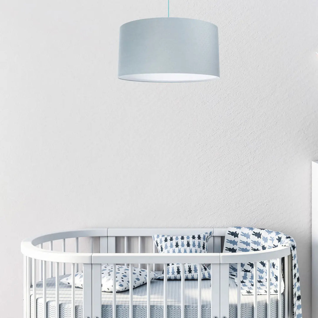 Suspension luminaire classic jasmin bleu pastel avec abat-jour cylindrique gris suspendue au-dessus dun lit bébé blanc