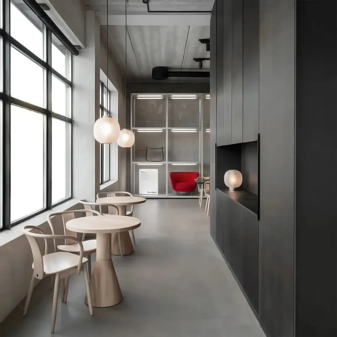 Suspension luminaire ovia en verre nervuré avec design moderne éclairant un café industriel chic avec fauteuil rouge