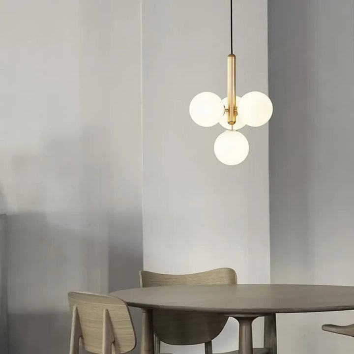 Suspension luminaire contemporaine golys avec tige centrale finition laiton et trois globes en verre givré apporte un luminaire design