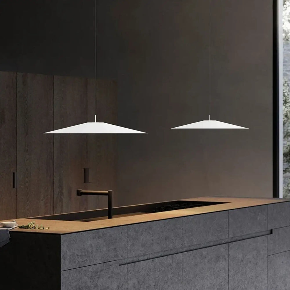 Deux suspensions luminaires blanches minimalistes au design géométrique suspendues au-dessus d’un îlot de cuisine moderne