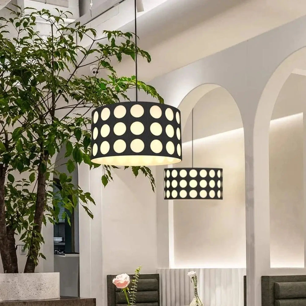 Suspension luminaire cylindrique noire nyxis avec motif de découpes circulaires blanches uniformes