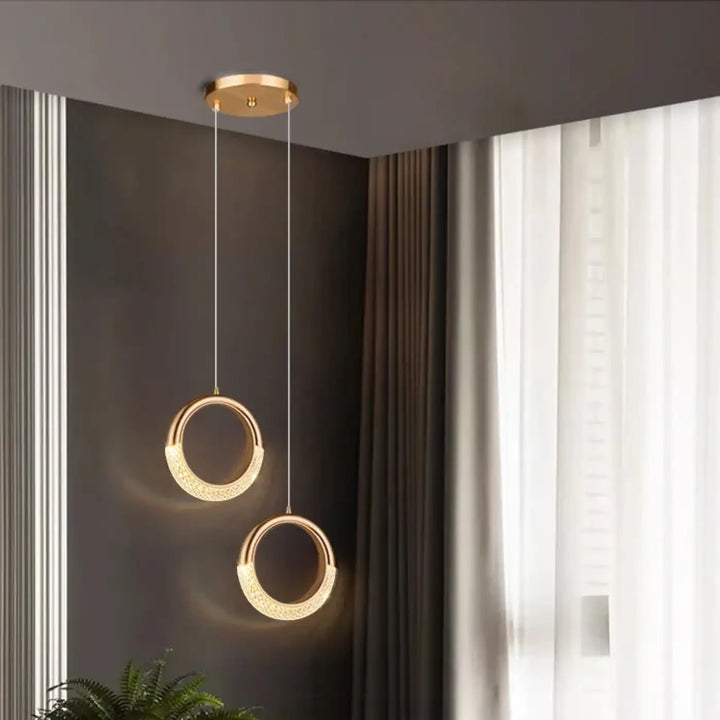 Deux suspensions luminaires décoratives dorées circulaires avec surface texturée et détaillée suspendues au plafond