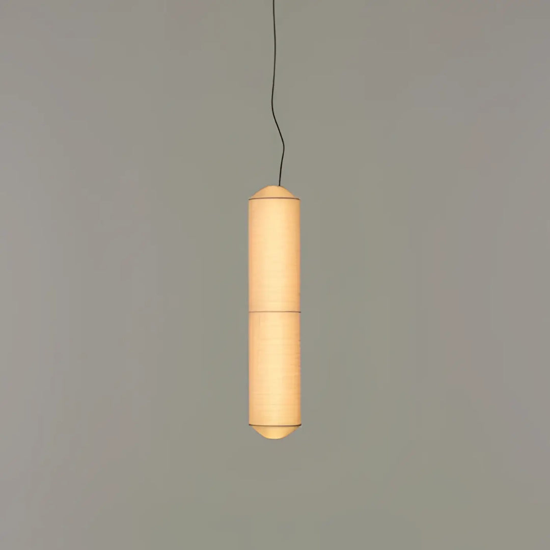 Suspension luminaire papieria en papier cylindrique chaleureux avec lumière douce et ridges verticales au-dessus d’une table