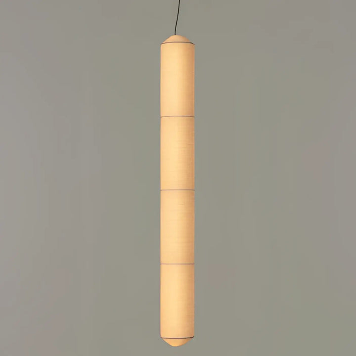 Suspension luminaire cylindrique en papier segmenté blanc offrant une lumière douce au-dessus d’une table