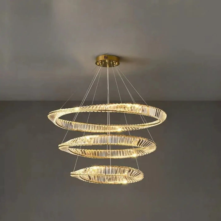 Lustre en spirale dorée avec trois anneaux entrelacés ornés d’accents en cristal transparent.