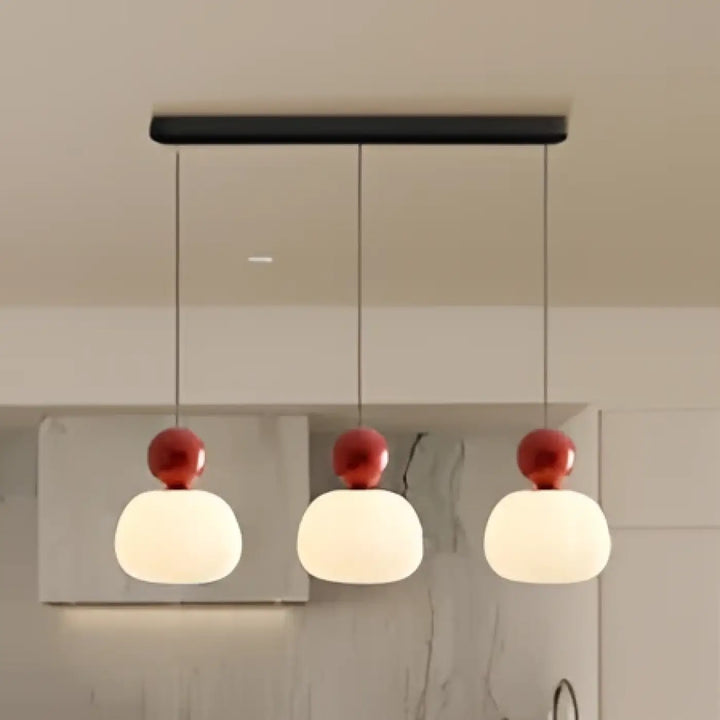 Suspension luminaire modern minimaliste avec trois globes en verre givré et accents rouges suspendus par câbles noirs