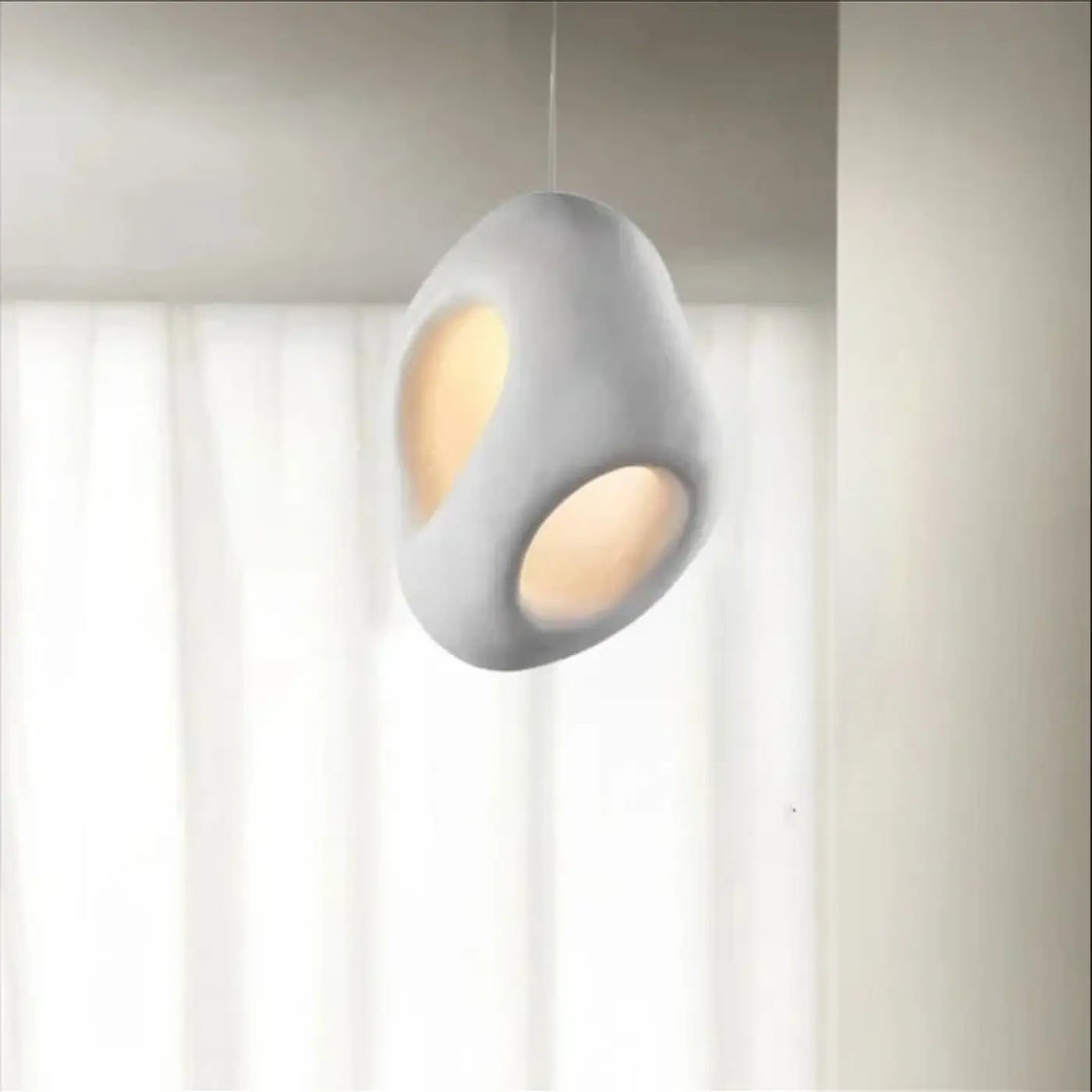 Suspension luminaire cavia en céramique mate grise avec deux découpes ovales diffusant une lumière chaude