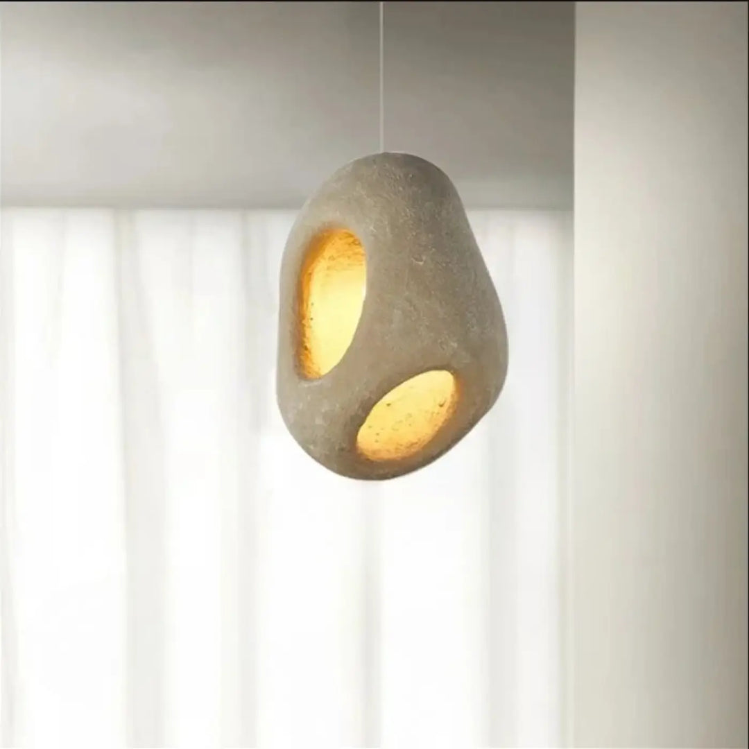 Suspension luminaire cavia en béton moderne avec surface texturée grise et deux ouvertures circulaires à ton chaud