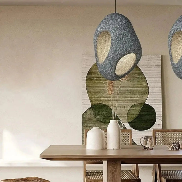 Suspension luminaire cavia gris texturé avec deux découpes ovales révélant une lueur intérieure chaude design aux