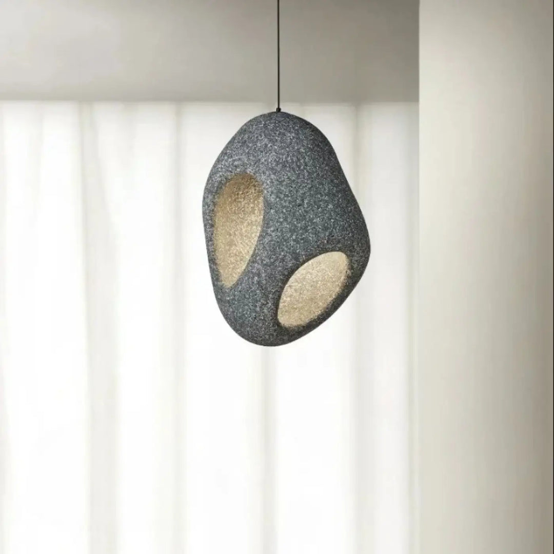 Suspension luminaire cavia gris texturé avec deux découpes ovales révélant une lueur intérieure chaleureuse en luminaire design aux