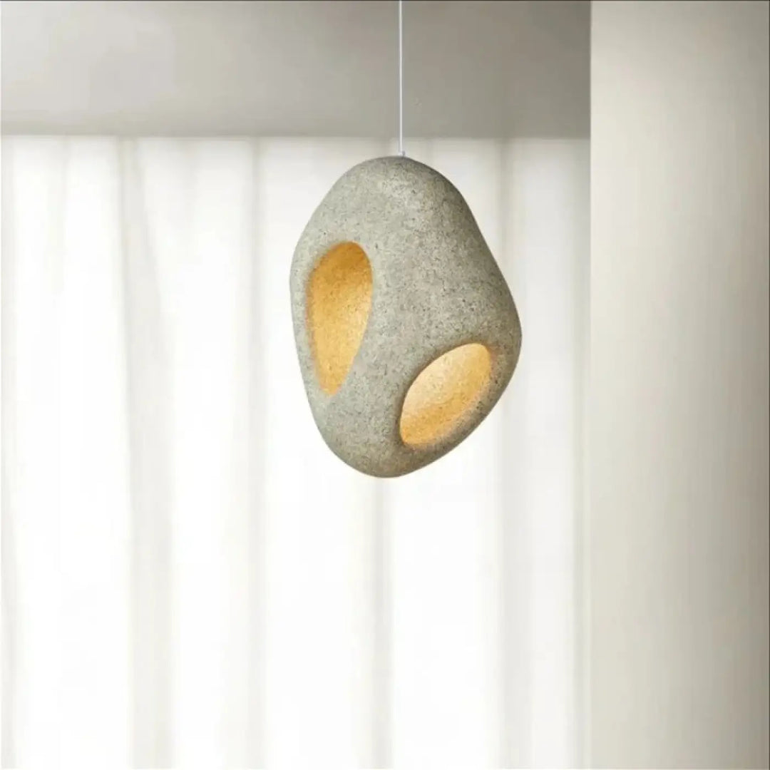 Suspension luminaire cavia en pierre grise texturée avec deux ouvertures circulaires à lumière chaude design luminaire aux