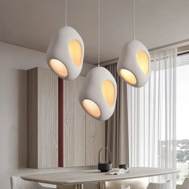 Suspension luminaire cavia avec trois lampes en céramique blanche texturée et intérieur jaune chaud en design luminaire aux