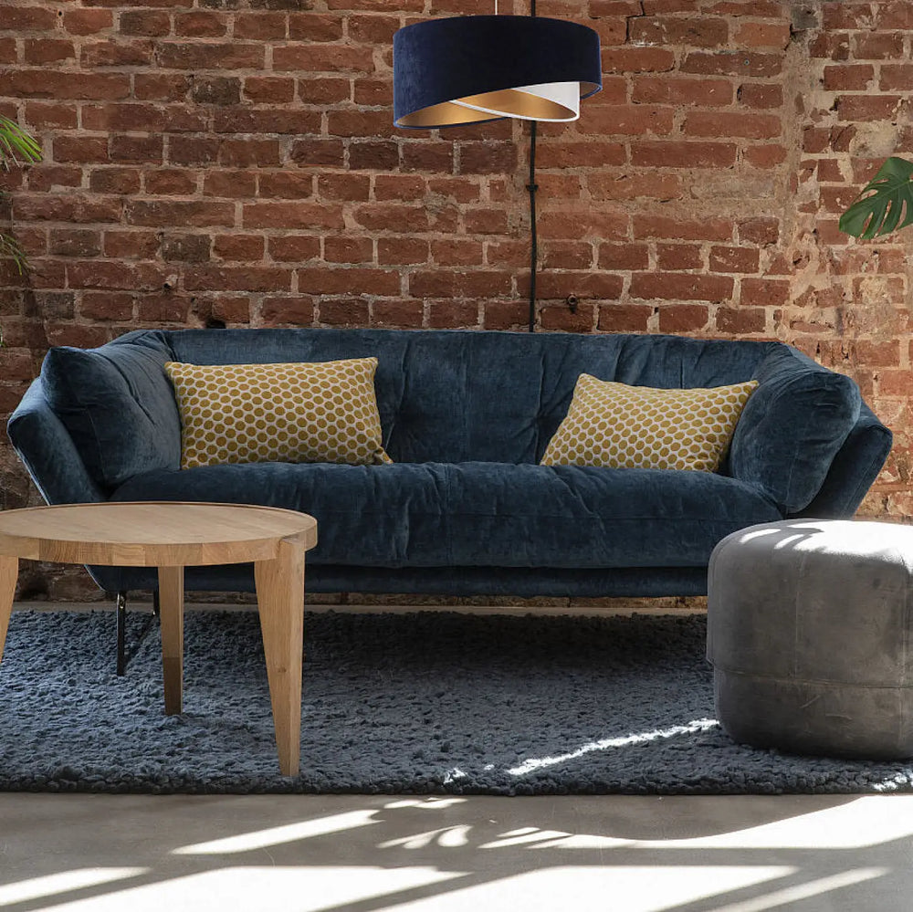 Canapé en velours bleu marine avec deux coussins jaunes moutarde à motif géométrique, design bleu marine suspension luminaire galaxy auric