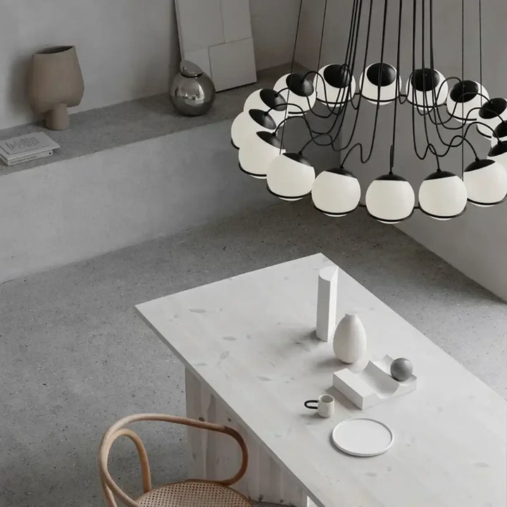Suspension luminaire cloudis avec plusieurs abat-jours sphériques en verre blanc suspendus par des cordons noirs