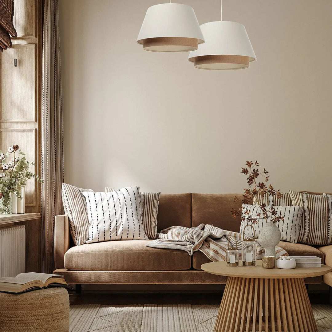 Beige velvet sofa with striped and solid throw pillows and textured blanket in a design crème suspension luminaire double abat setting