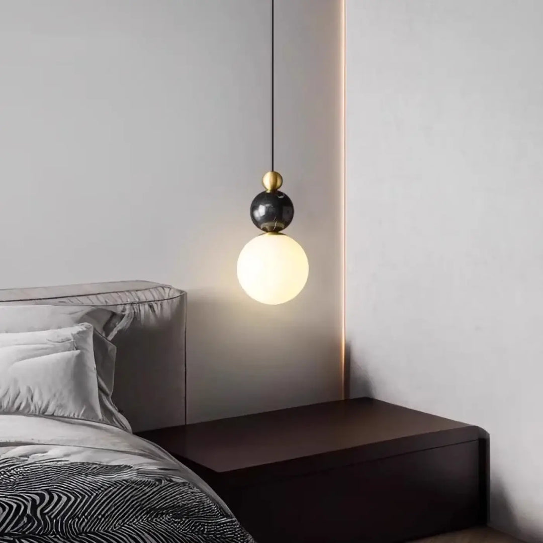 Suspension luminaire eluna avec sphère en marbre noir, accent doré et globe en verre dépoli pour un design moderne