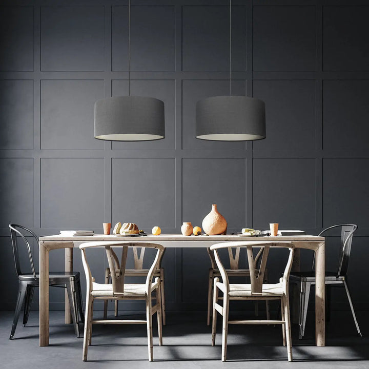 Suspension luminaire design graphite suspendue au-dessus d’une table à manger minimaliste en bois clair