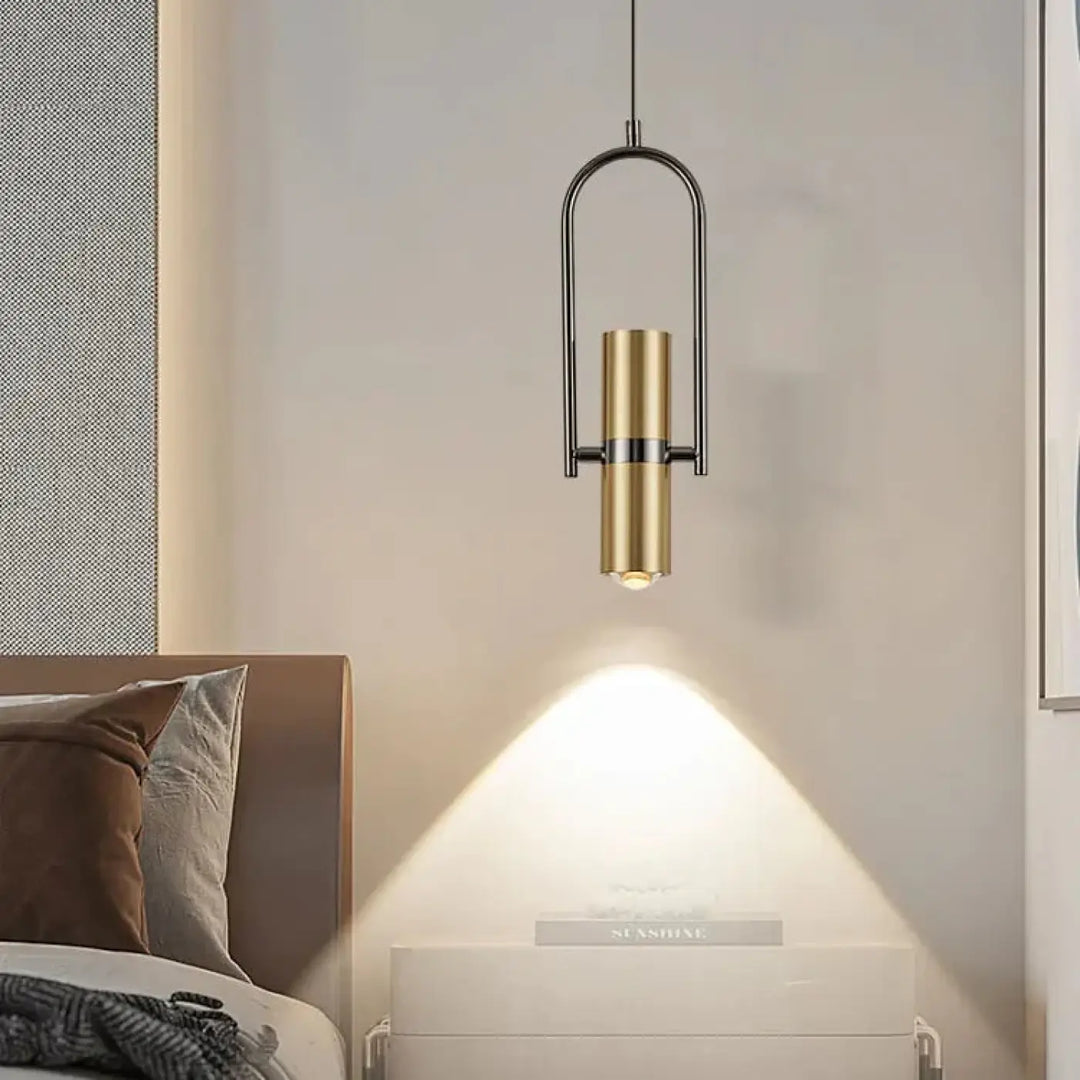 Suspension luminaire sigo avec corps cylindrique en laiton brossé et cadre noir spot orientable au-dessus de table de chevet