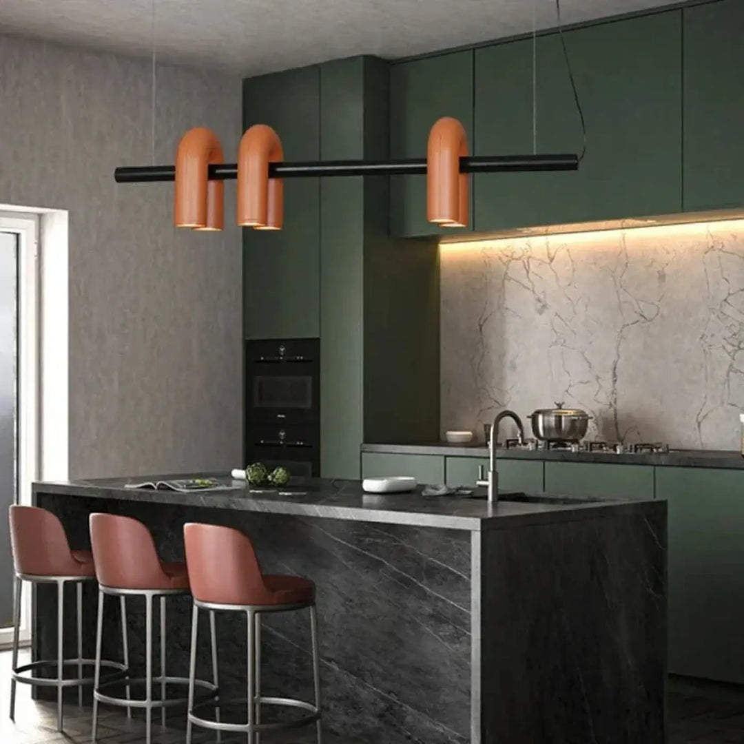 Suspension luminaire onda avec design en cuivre et bras cylindriques noirs suspendue au-dessus d’un îlot en marbre noir