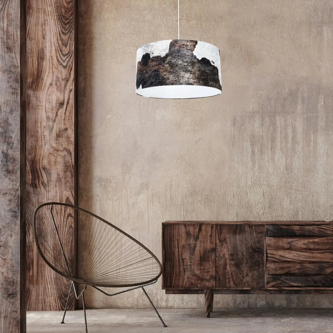 Suspension luminaire safari marron blanc en forme cylindrique avec motif peau de vache noir et blanc suspendue par un cordon fin