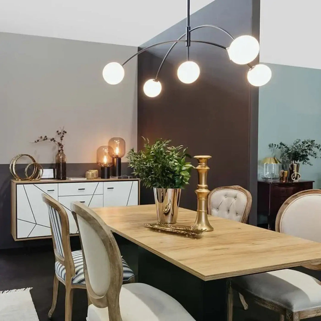 Suspension luminaire laithy avec vase métallique doré et plante verte pour une lumière douce en salle à manger