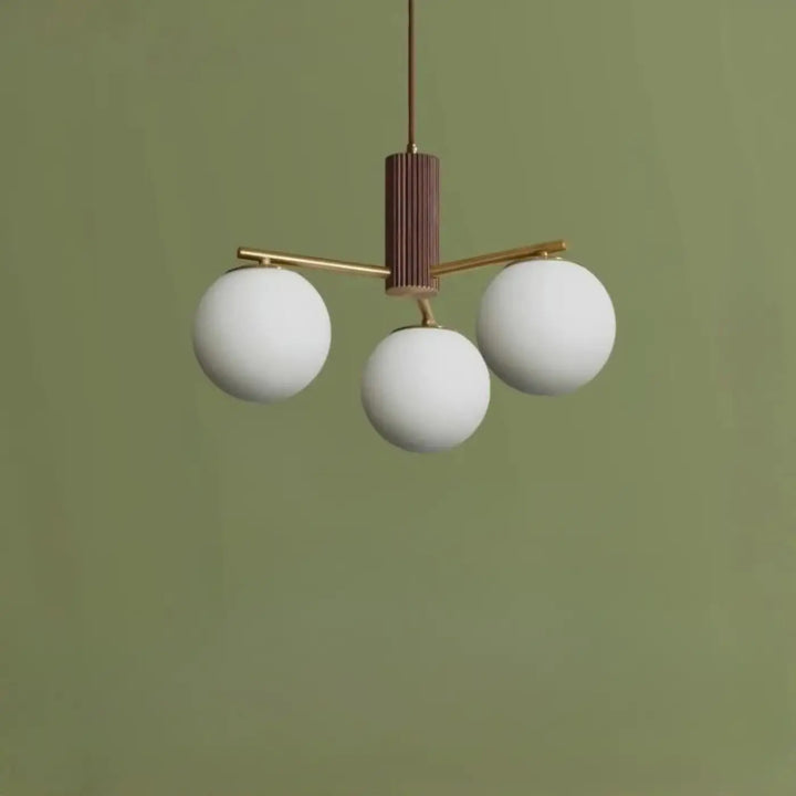 Suspension luminaire juglys avec trois sphères lumineuses blanches en verre et corps cylindrique vertical en laiton