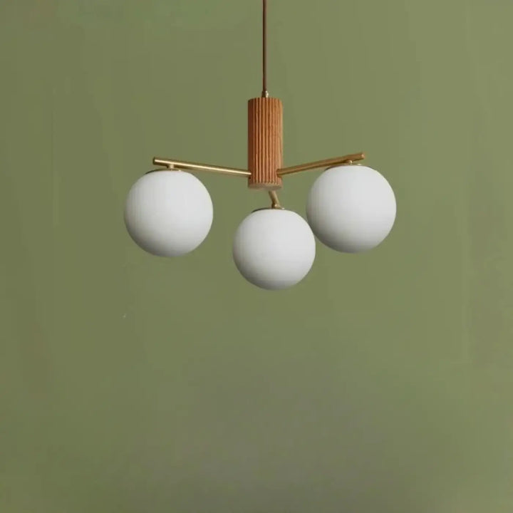 Suspension luminaire juglys avec sphères lumineuses en verre blanc mat et cadre en laiton chaud avec colonne centrale en bois texturé
