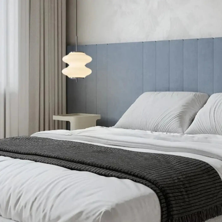Suspension luminaire kalim avec abat-jour en verre blanc à formes arrondies suspendue au-dessus du lit