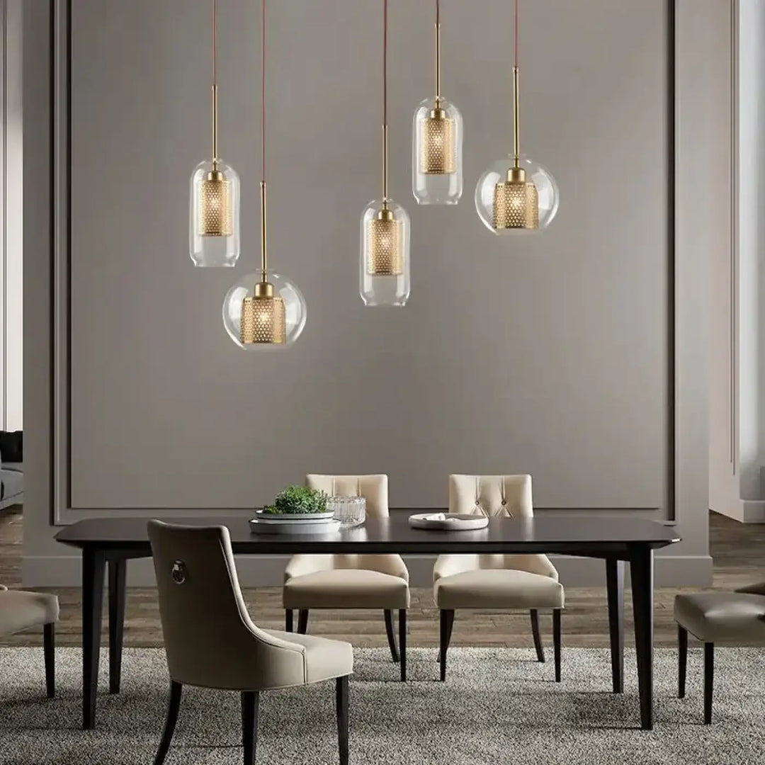 Cinq suspensions luminaires zelorr avec abat-jour en verre transparent et intérieur perforé en métal doré