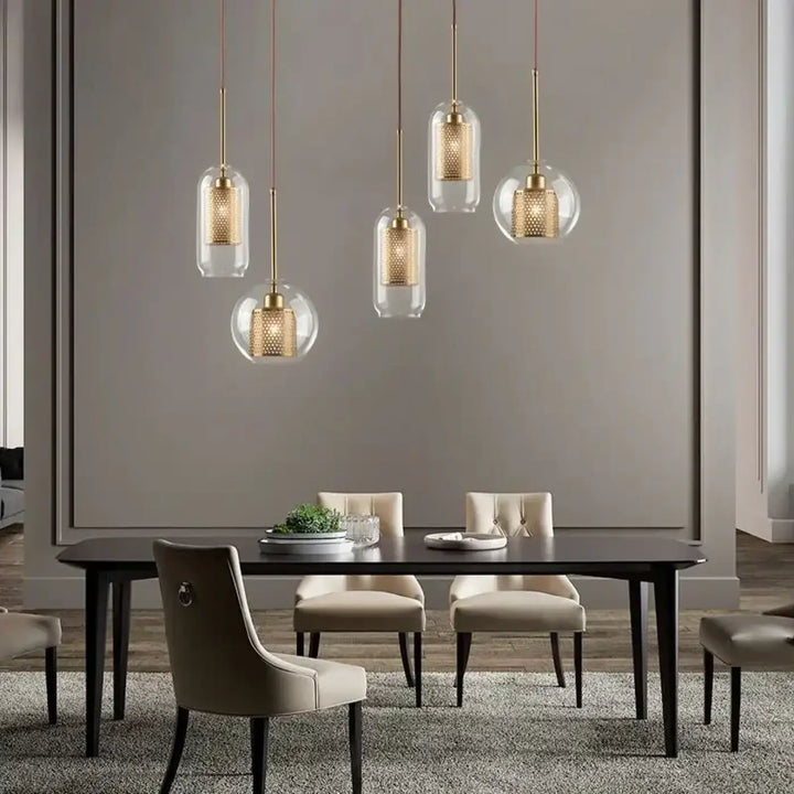Cinq suspensions luminaires zelorr avec abat-jour en verre transparent et intérieur perforé en métal doré